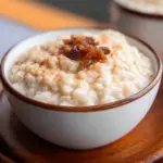 Creamy crockpot rice pudding served in a bowl with a sprinkle of cinnamon.