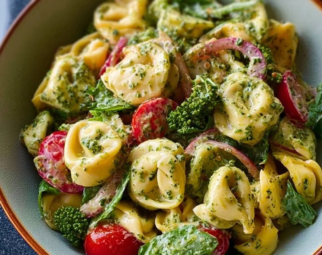 A colorful Pesto Tortellini Salad with fresh vegetables and herbs