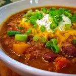 Delicious spicy pumpkin chili served in a bowl with toppings.