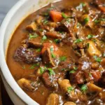 Delicious beef and mushroom stew in a rustic bowl, garnished with herbs.