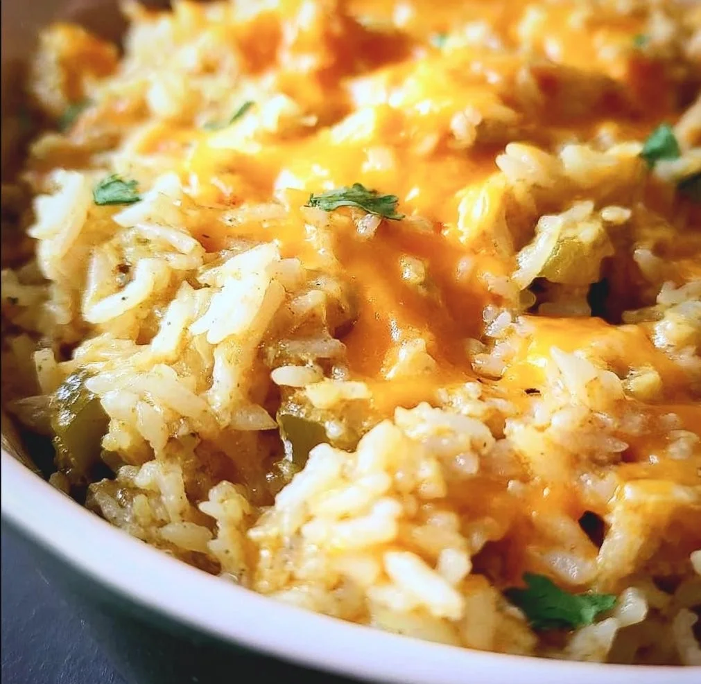 Cheesy green chili rice dish garnished with herbs and served in a bowl