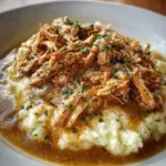 Crockpot shredded chicken gravy served over mashed potatoes in a bowl