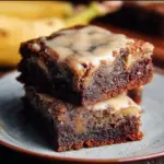 Delicious banana bread brownies served on a plate with chocolate drizzle