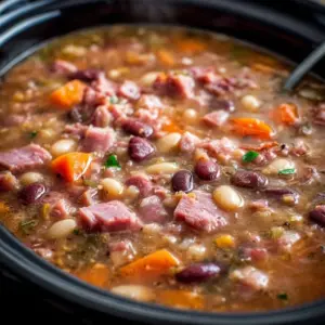 Bowl of Crockpot ham and bean soup garnished with herbs and served with bread.