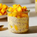Bowl of mouthwatering mango overnight oats topped with fresh mango slices and coconut.