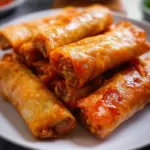 Plate of crispy Chinese vegetable spring rolls with fresh ingredients.