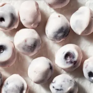 A bowl of yogurt covered blueberries ready to enjoy as a healthy snack.