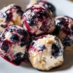 Blueberry Cheesecake Protein Bites on a plate garnished with fresh blueberries