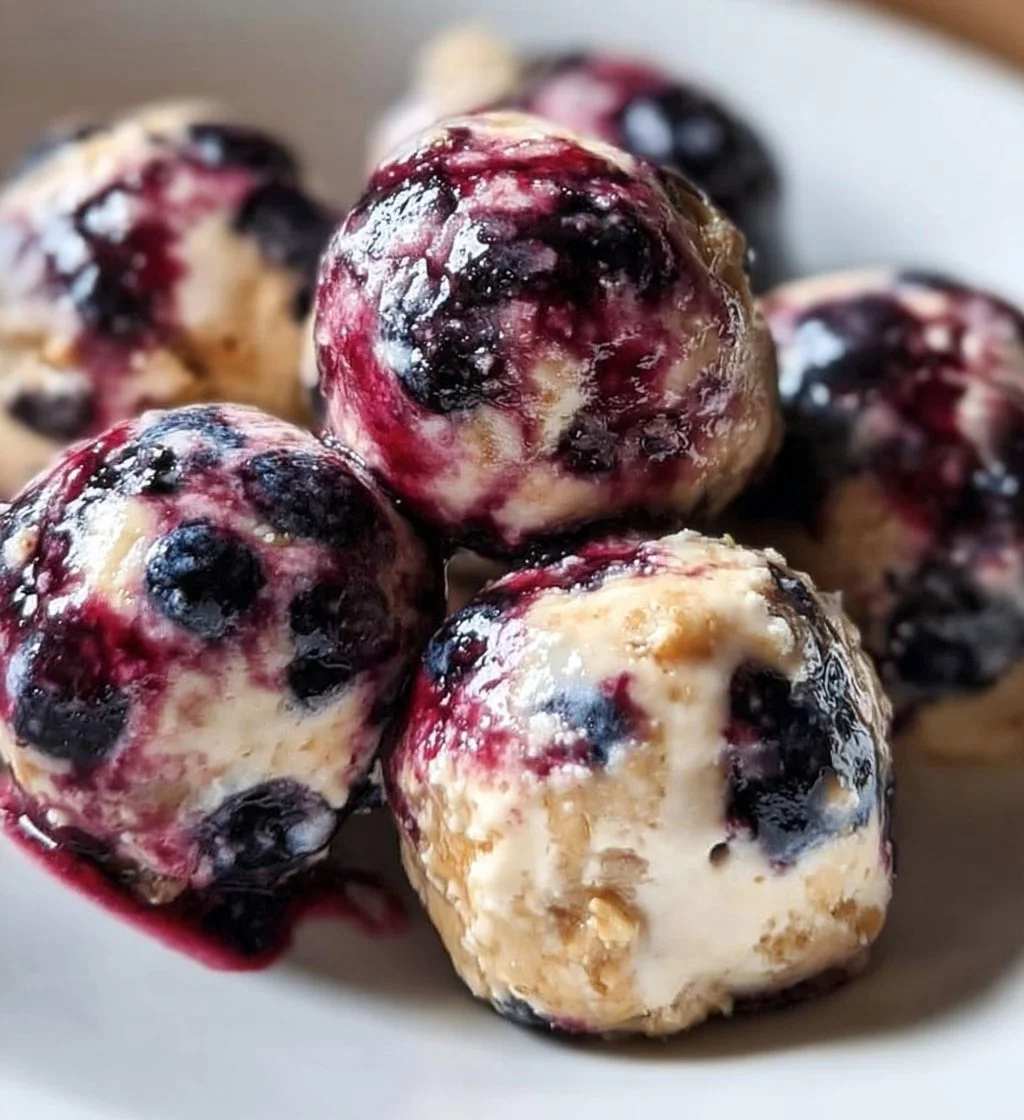 Blueberry Cheesecake Protein Bites on a plate garnished with fresh blueberries