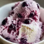 Blueberry cottage cheese ice cream in a bowl with fresh blueberries on top.