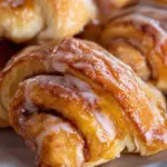 Freshly baked cinnamon crescent rolls topped with icing on a plate