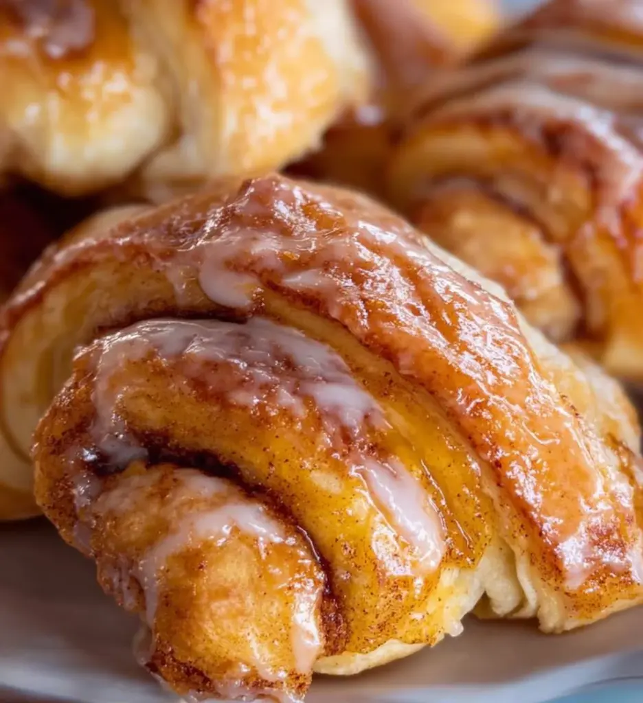 Freshly baked cinnamon crescent rolls topped with icing on a plate