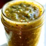 Delicious Mexican tomatillo green sauce in a bowl, fresh ingredients around.