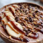 Delicious Snickers Smoothie Bowl topped with nuts, chocolate, and banana slices